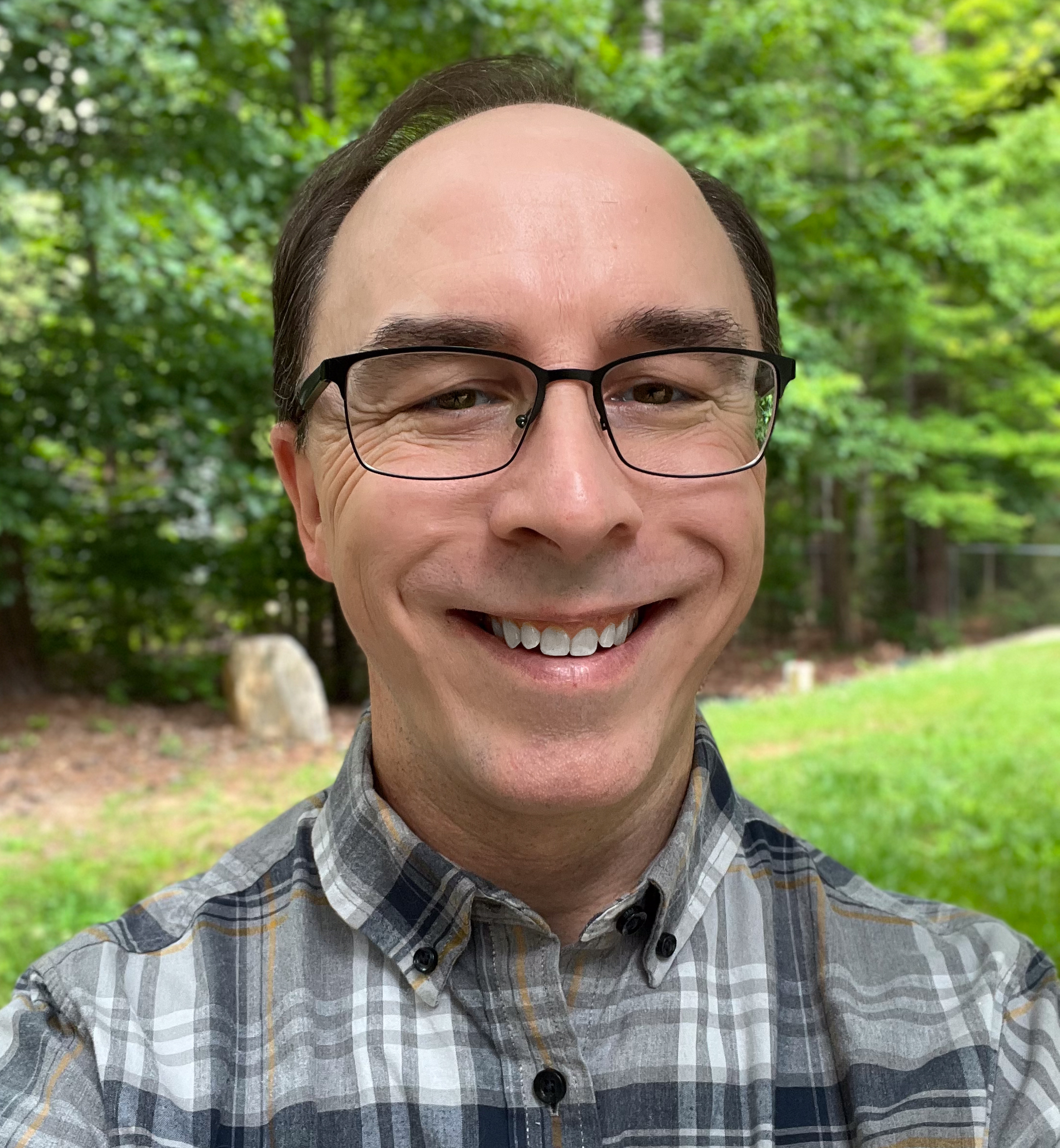 Michael Wendel smiling in a plaid shirt with glasses